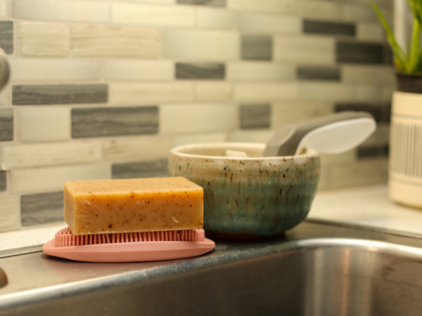 White Tea & Ginger Goat Milk Soap Bar sitting on a silicone soap lift on the edge of a kitchen sink