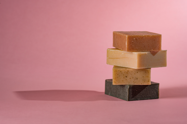 Friendly Goods Goat Milk Soap Bars Stacked, unwrapped, on a pink background