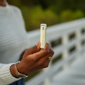 300x300 Image of a Black woman's hand holding a Friendly Goods lip balm tube towards the camera