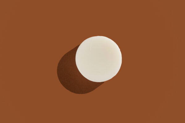 Coconut Moonlight solid conditioner bar against a brown background