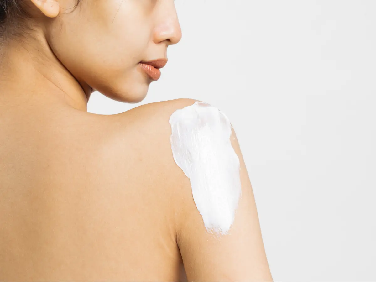 Stock image of a female applying lotion to her shoulder